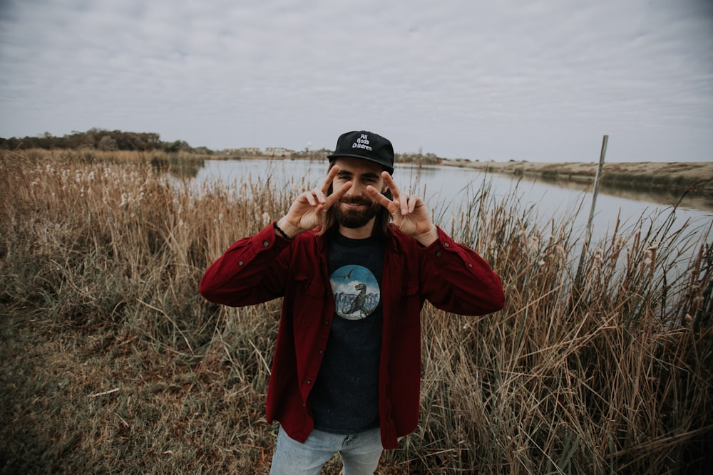 man standing on grass field beside river