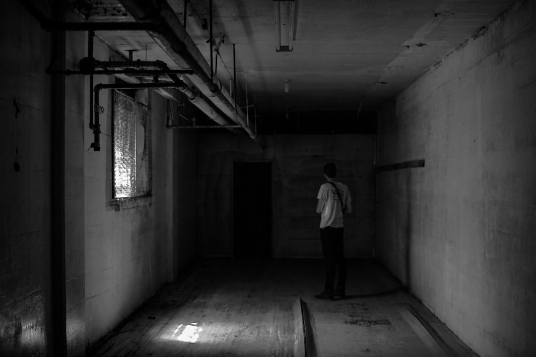 grayscale photo of man near wall