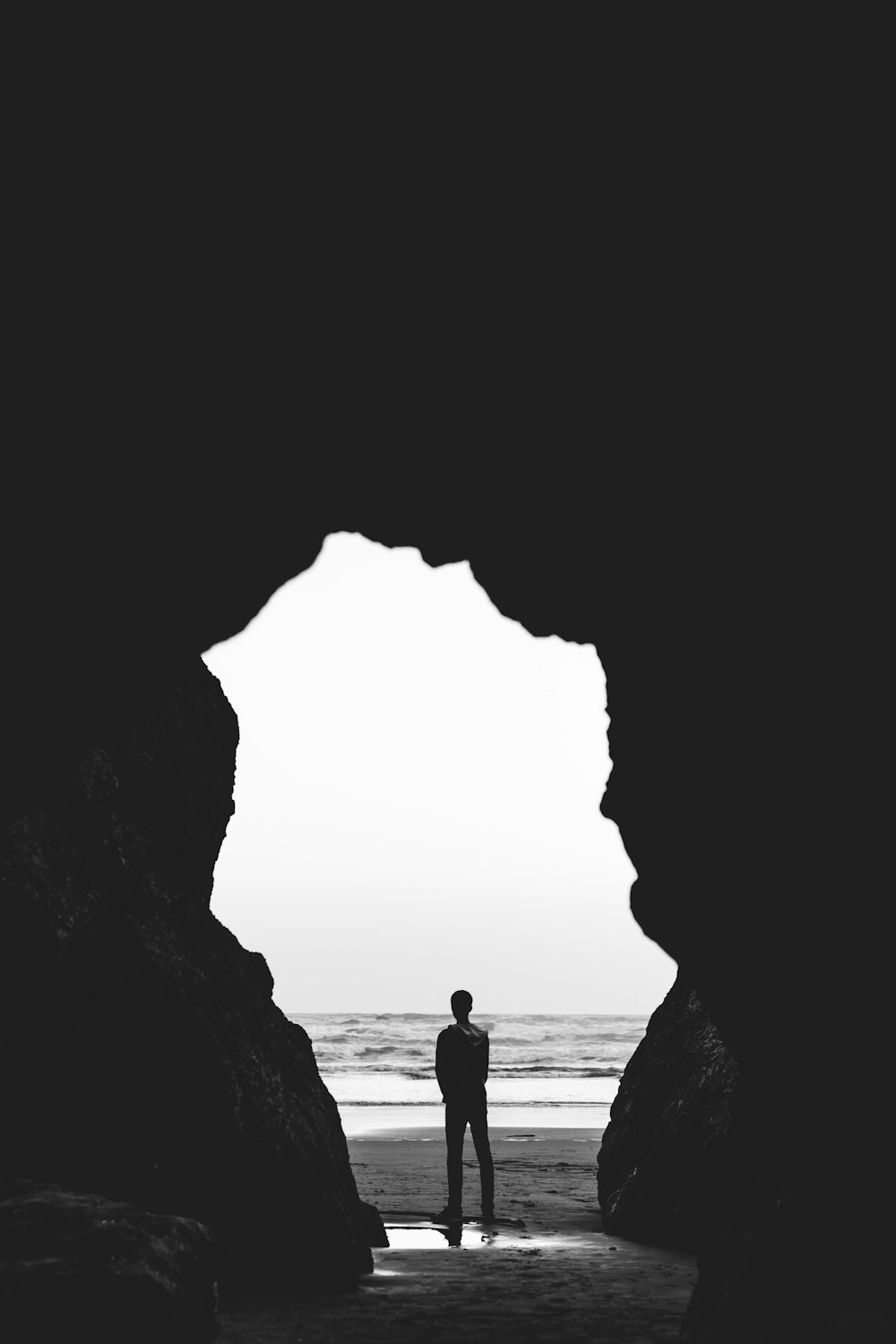 해변에 서 있는 남자의 회색조 사진