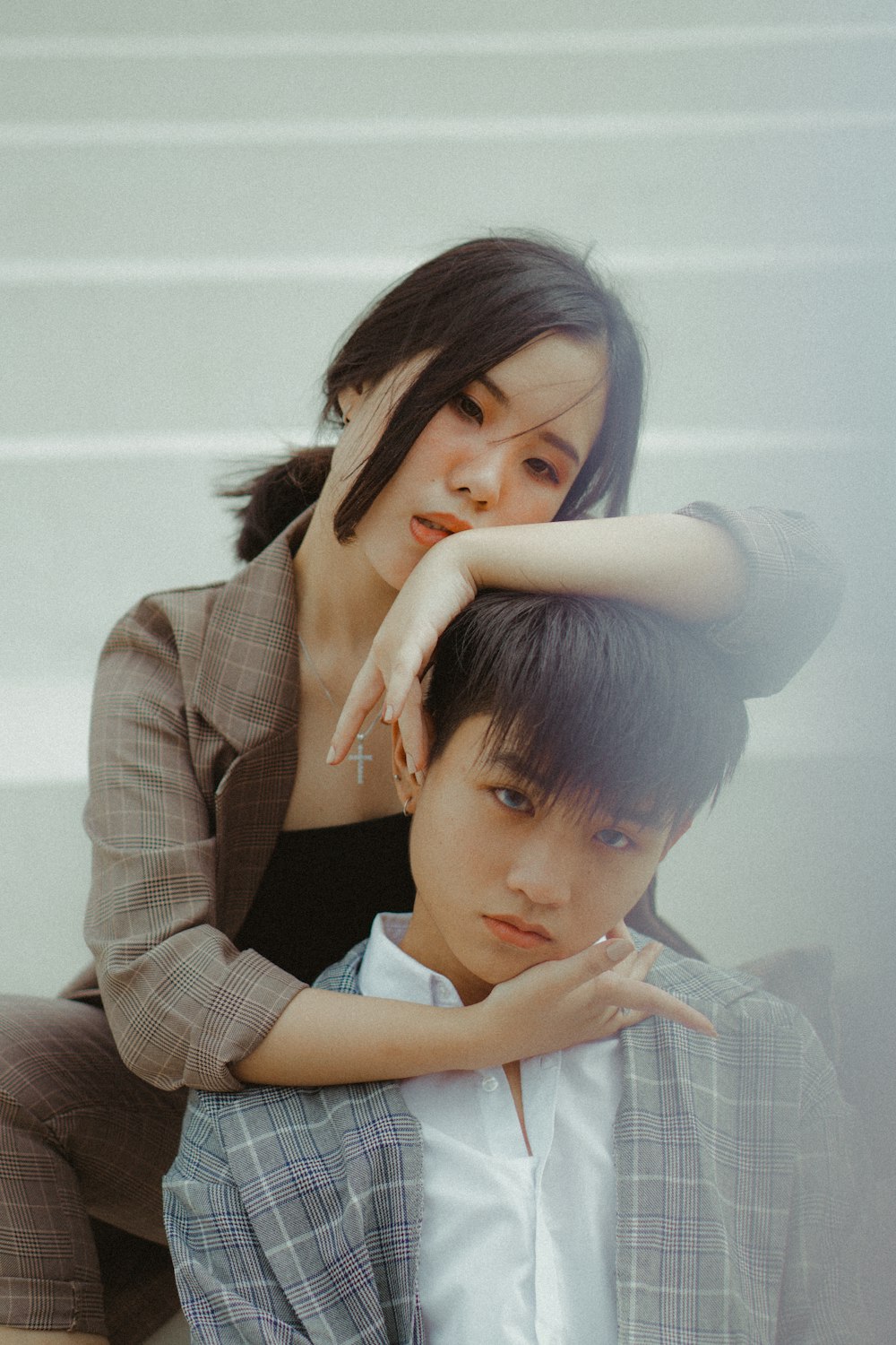 woman holding boy's head near white wall