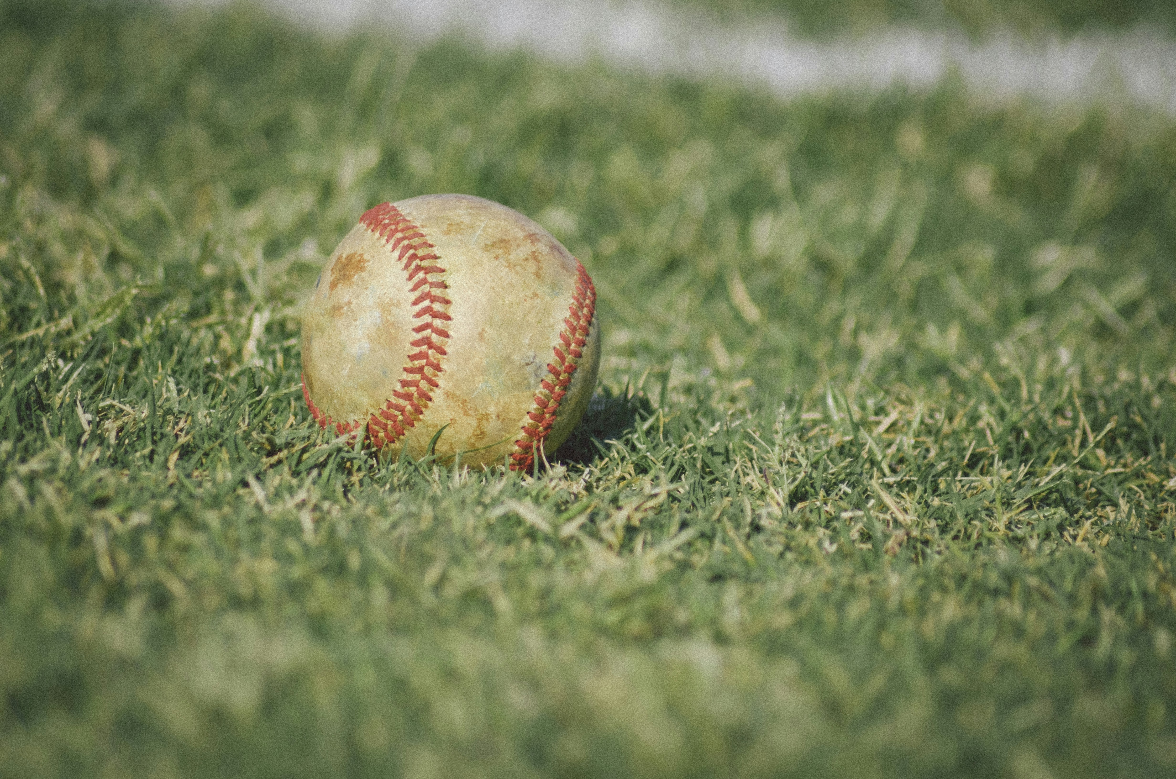 white and red baseball on green grass