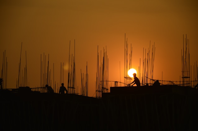 Construction workers collaborating on a modern building site at sunset with golden light.