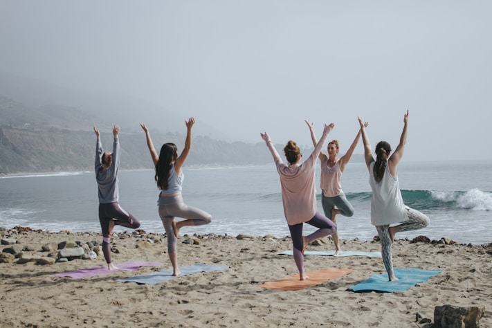 Group yoga session on a beach, highlighting the importance of fitness and mental health 