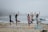 A group of people practicing yoga at sunset on a beach.