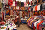 woman in store with display of assorted shirts and textiles