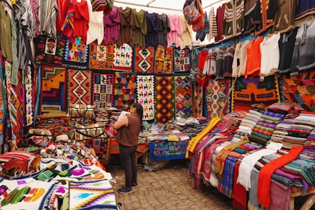 woman in store with display of assorted shirts and textiles