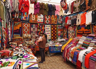woman in store with display of assorted shirts and textiles