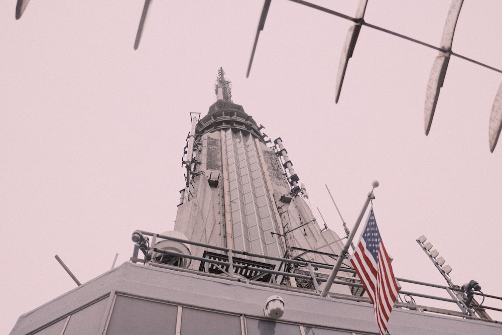 낮 동안 미국 국기와 함께 회색 콘크리트 타워의 낮은 각도 사진