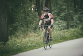A cyclist wearing sleek cycling glasses riding through a forest trail.