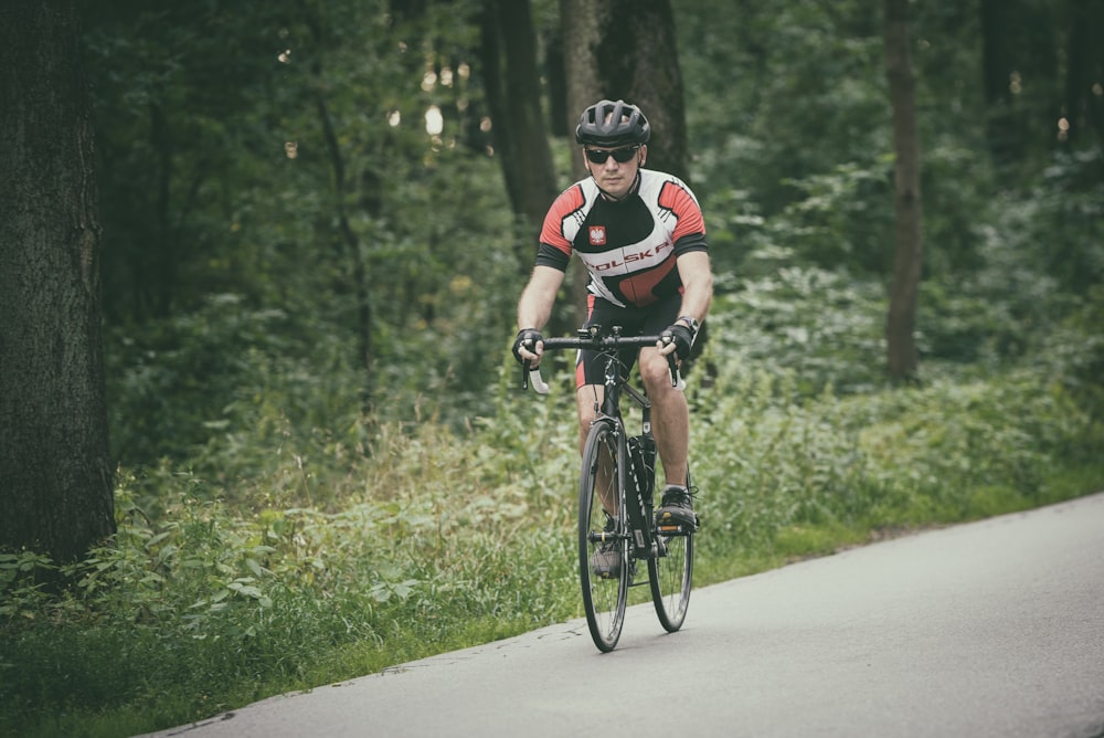 man riding bike at the road near trees during day