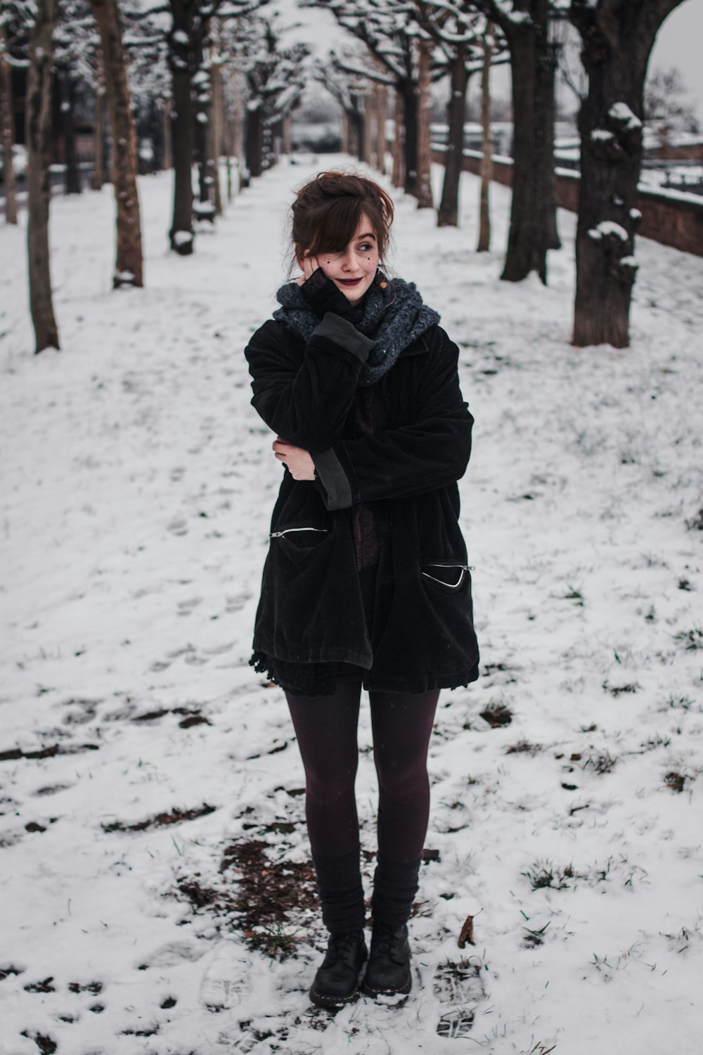 woman in black coat standing near trees