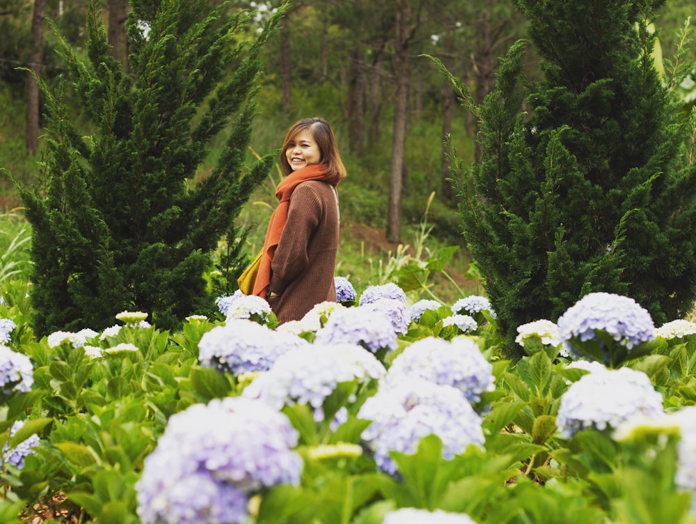 woman in brown jacket standing on field of flowers
