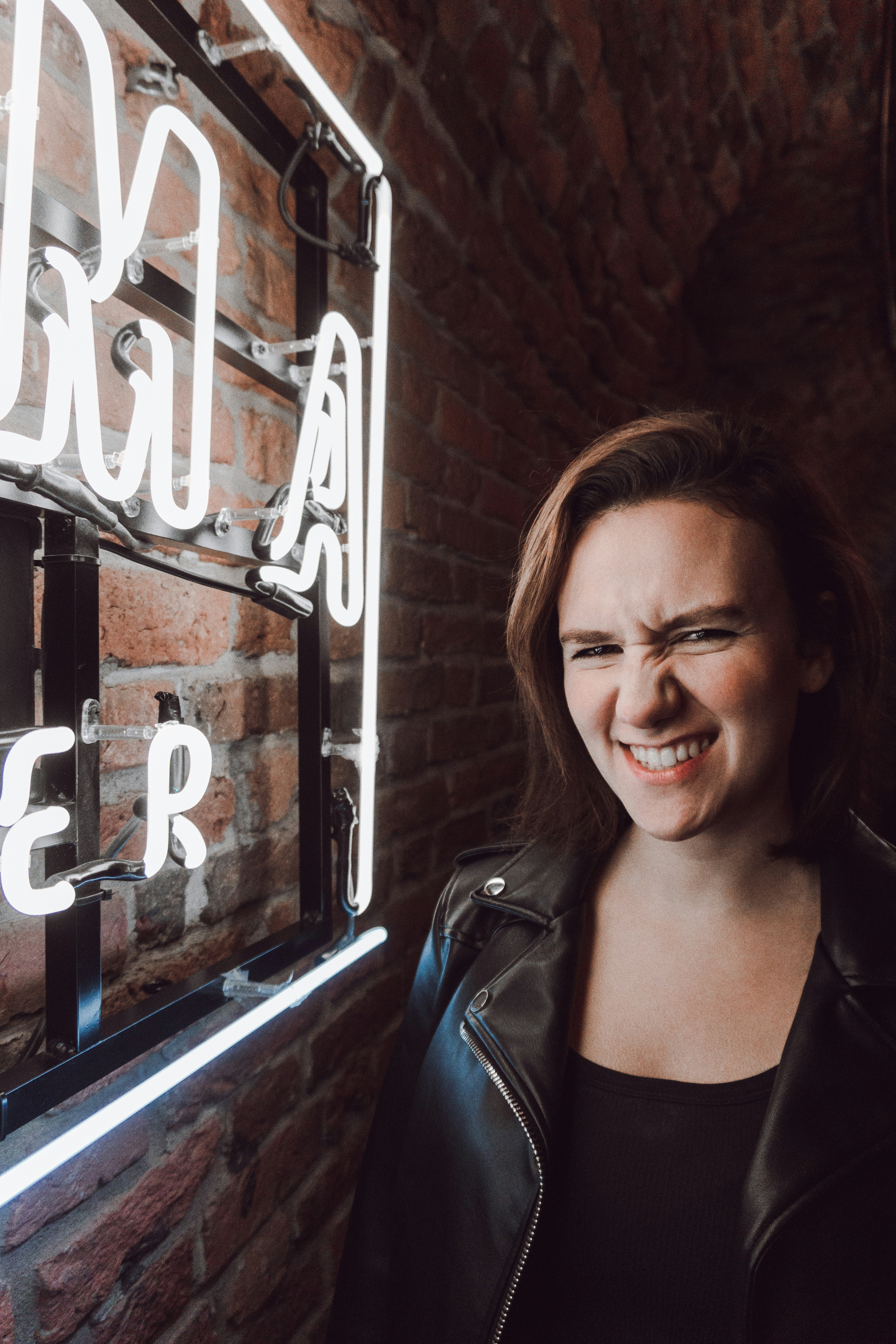 chica sonriendo cerca de la luz de neón encendida