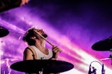 Drummer energetically playing in a vibrant music venue.
