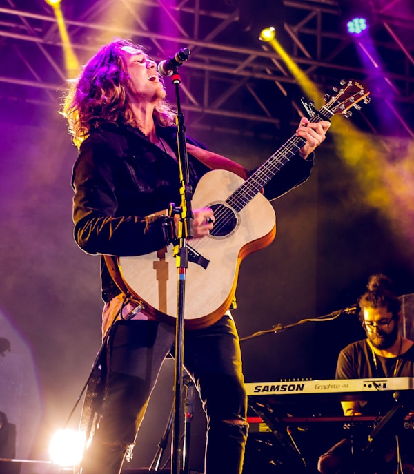 man singing and playing guitar on stage