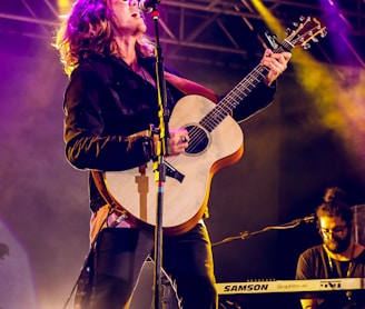 man singing and playing guitar on stage