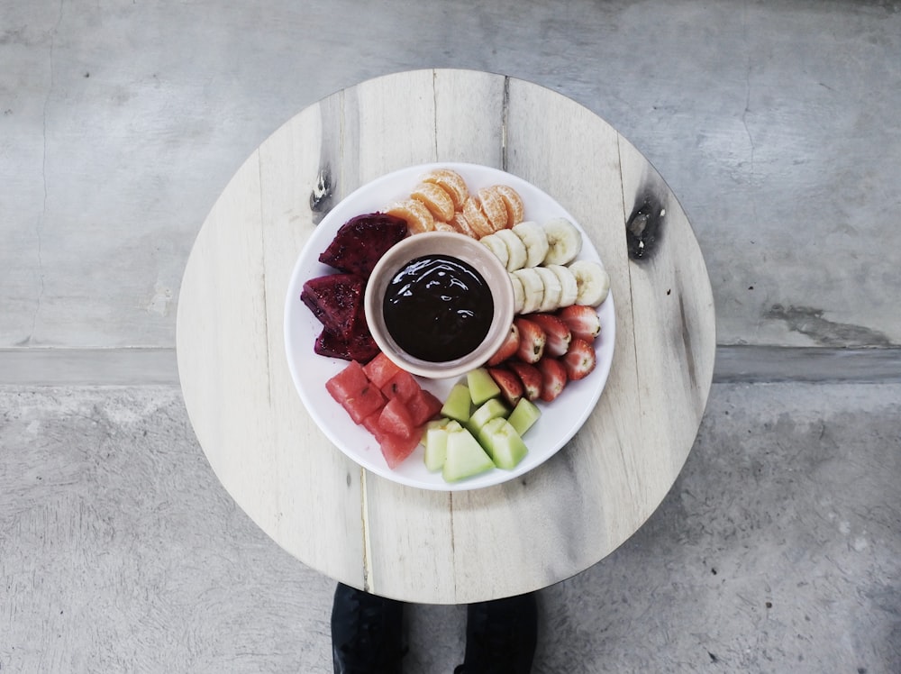 white coffee cup and sliced fruits on white plate