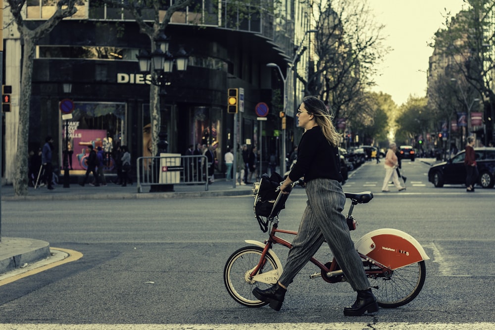 woman walking on pedestrian lane with bicycle