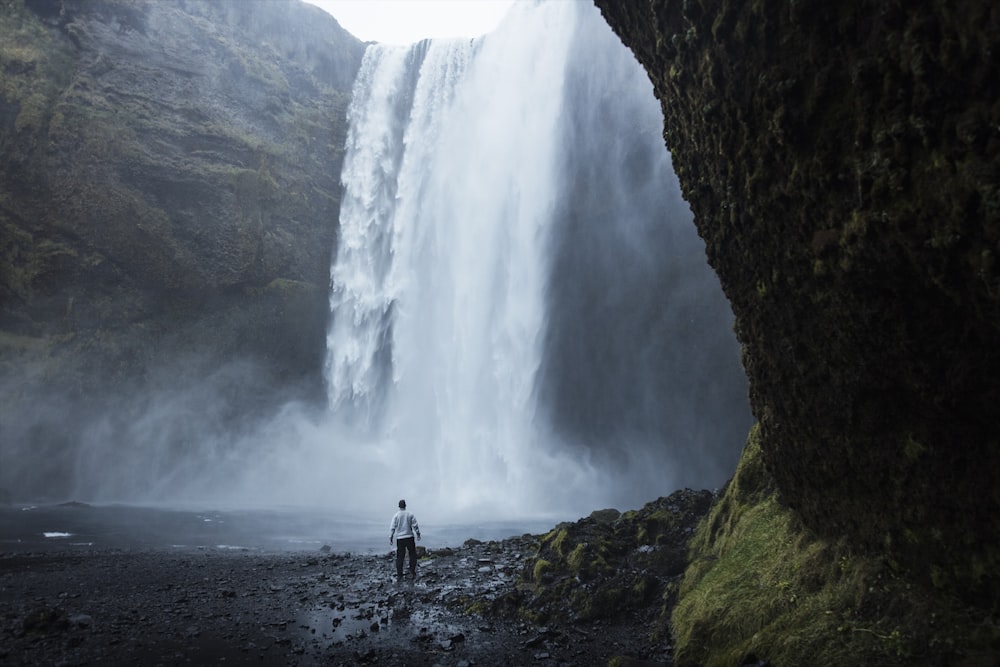 man standing near waterfalls during daytime