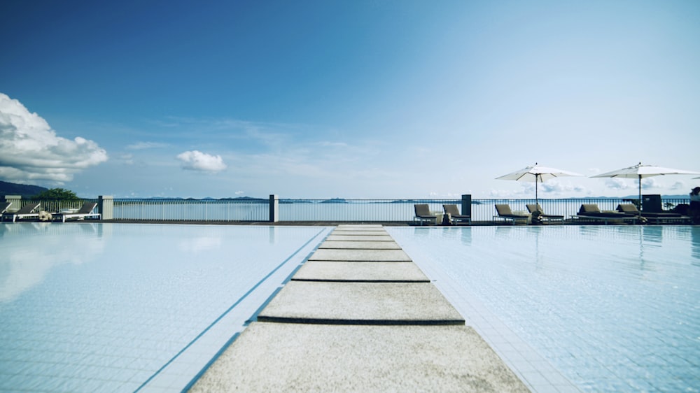 concrete pathway in between pool during daytime