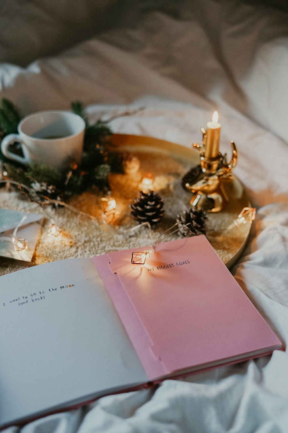 candle with candle holder and teacup on bed