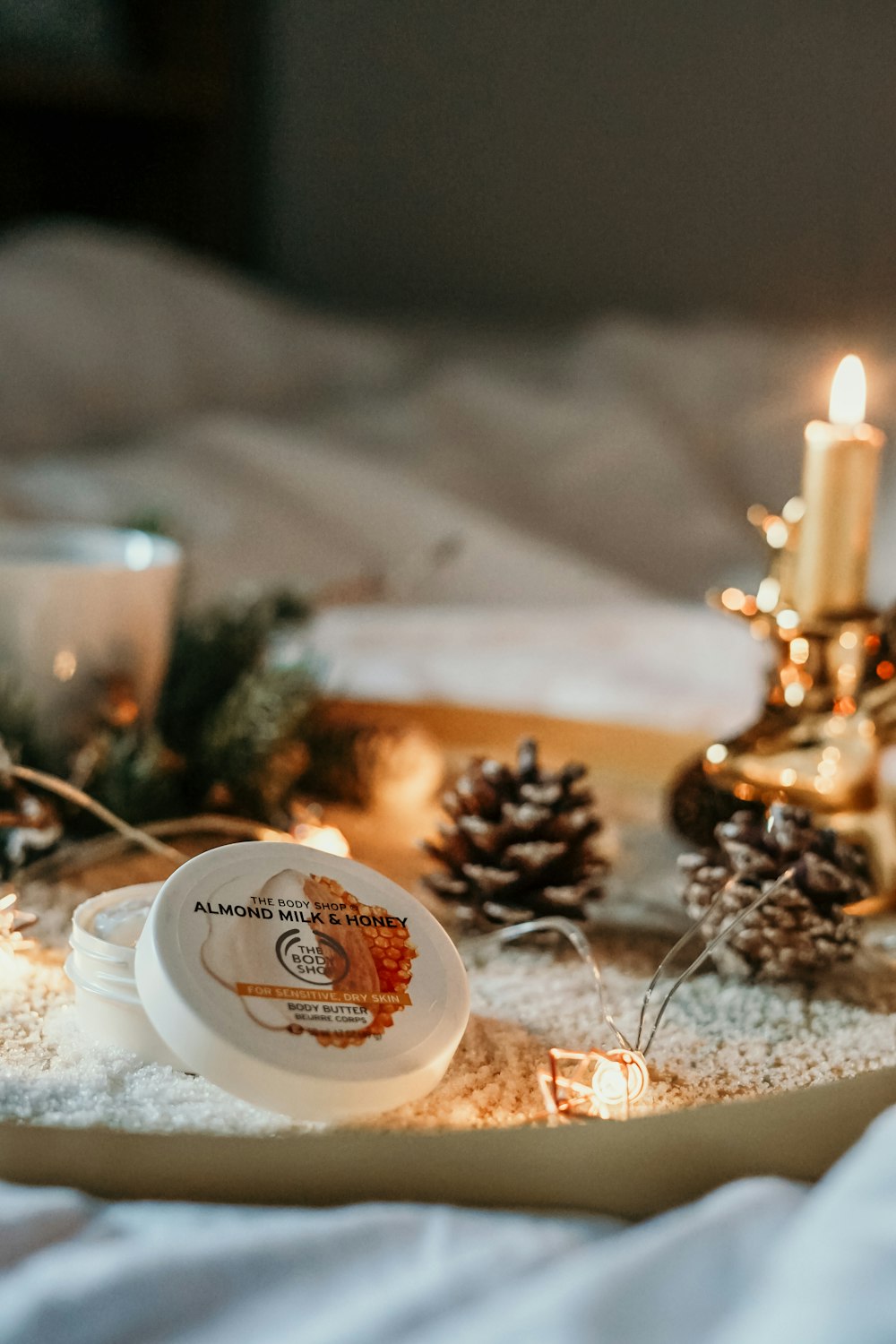 lit candle near pine cone and cosmetic case