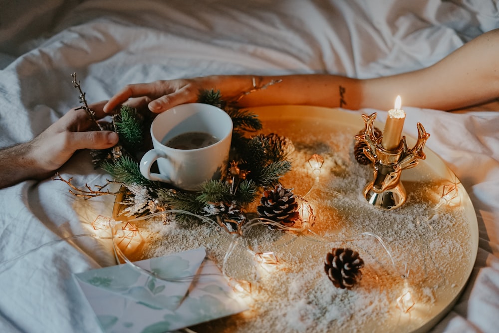 white ceramic cup on table beside pine cones