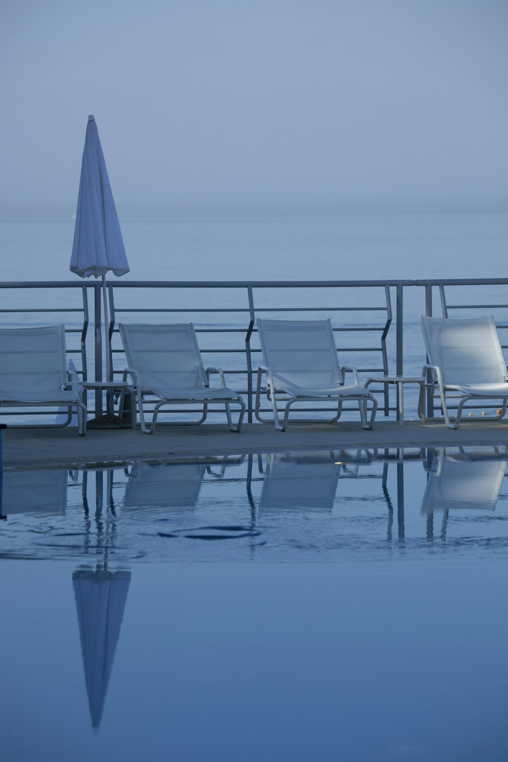 Quatre chaises longues grises près de la piscine d’eau