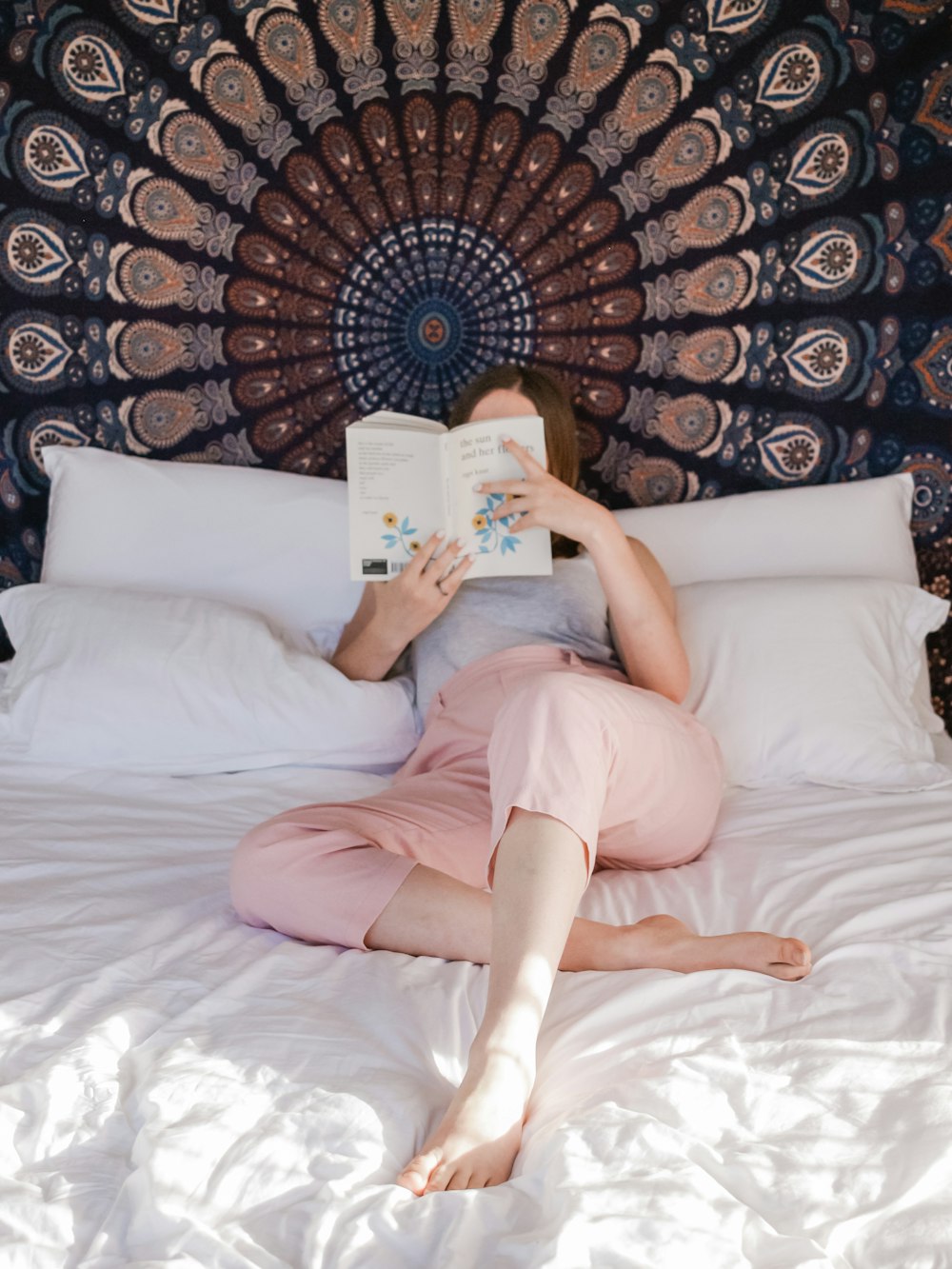 ベッドに横たわりながら本を読む女性