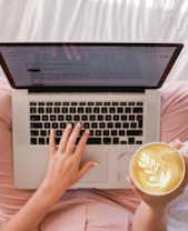 person using MacBook Pro and holding cappuccino