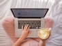 person using MacBook Pro and holding cappuccino