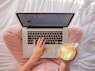 person using MacBook Pro and holding cappuccino