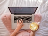 person using MacBook Pro and holding cappuccino