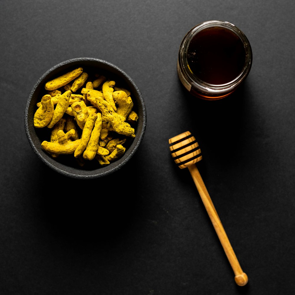 food in black bowl near honey on jar beside honey dipper