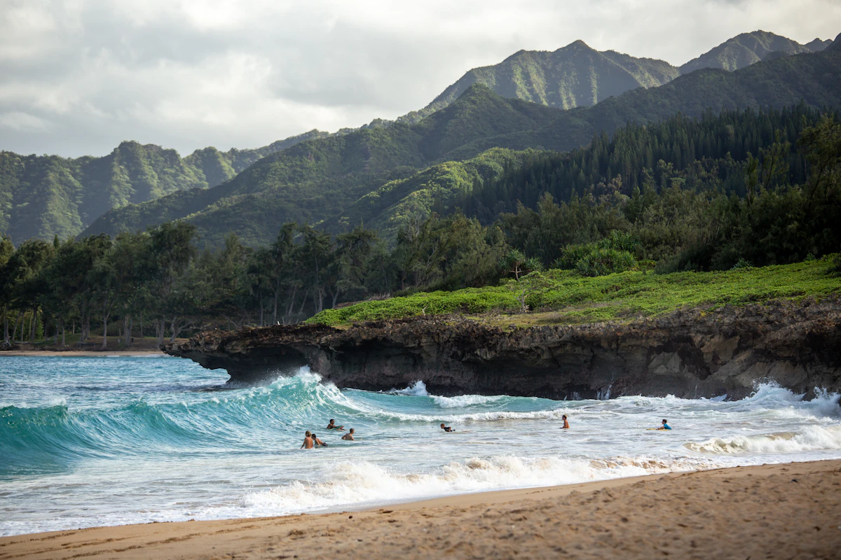 Large ocean waves under stormy skies near a tropical coastline