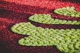 Clusters of green apples are artistically arranged against a backdrop of vibrant red cranberries, creating a striking contrast between the colors.