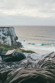 A cozy coastal reading nook with textured pillows and a view of the sea