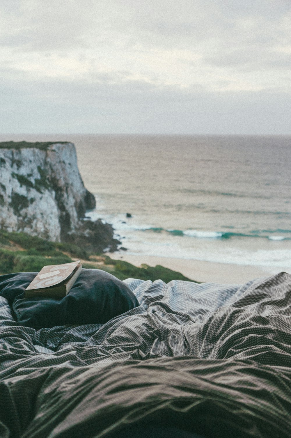 book on gray pillow on bed near seat during daytime