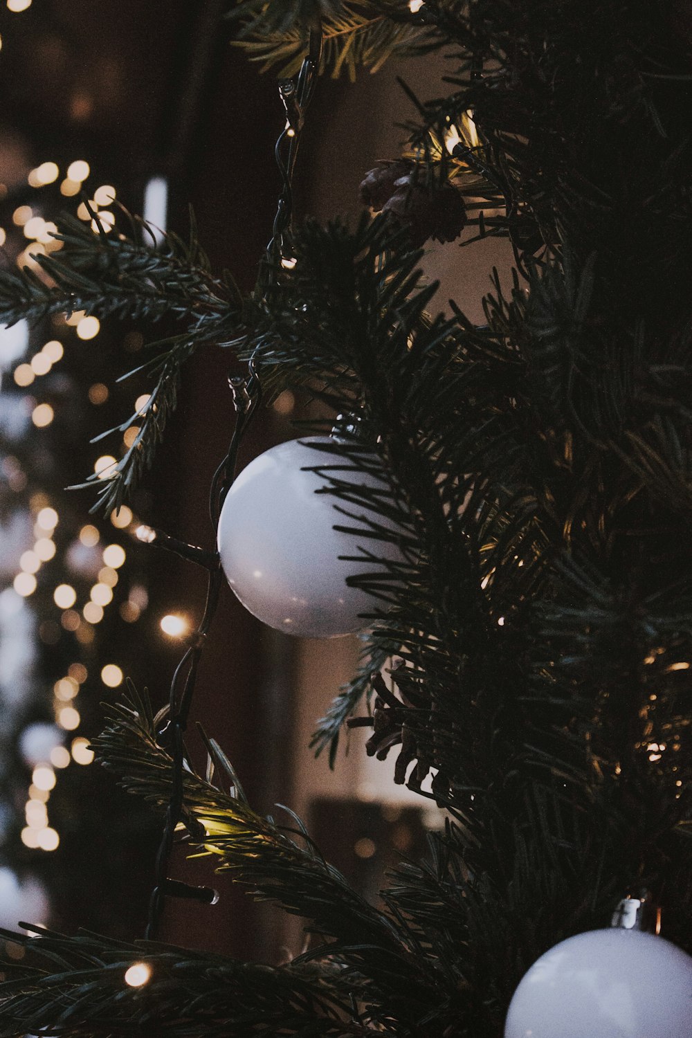 white baubles and green string light on Christmas tree