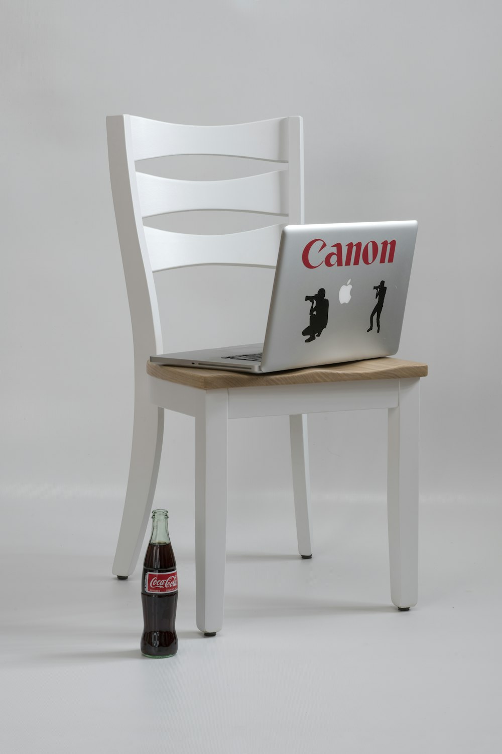 MacBook Pro on white-and-brown wooden table near Coca-Cola glass bottle