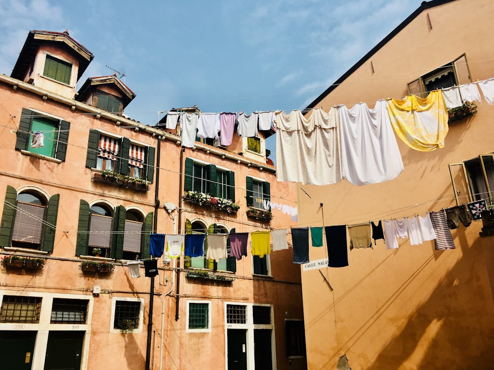 clothes hanged on strings near concrete buildings during daytime
