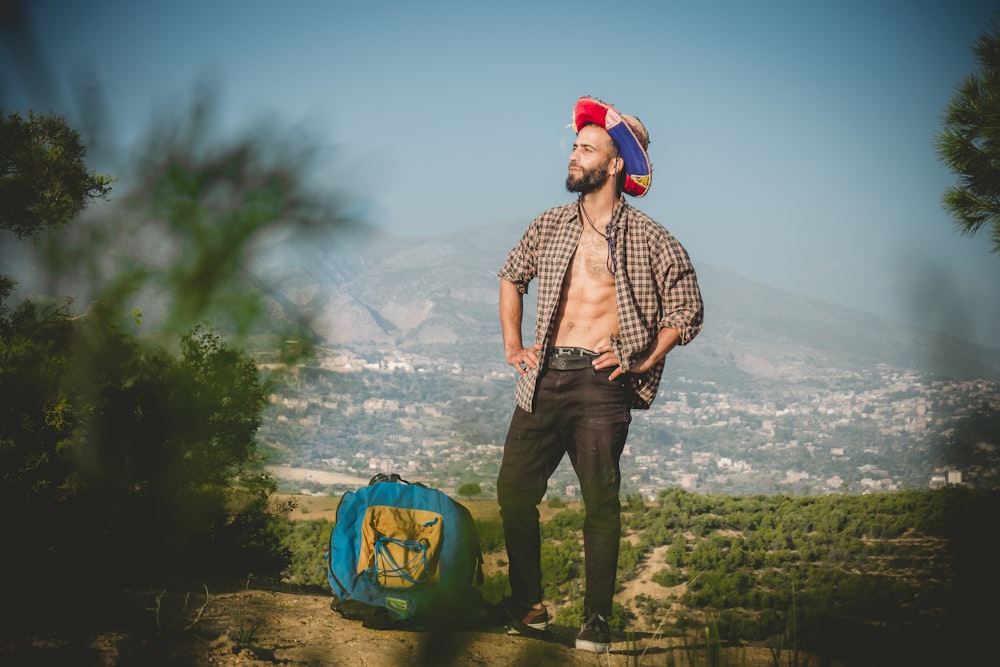 man standing beside blue bag wearing red and blue hat