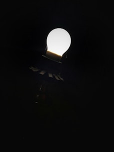 A bright light bulb glowing against a dark background symbolizing ideas.