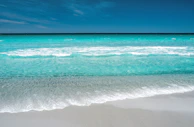 A panoramic view of a serene beach with turquoise waves gently caressing the sand.