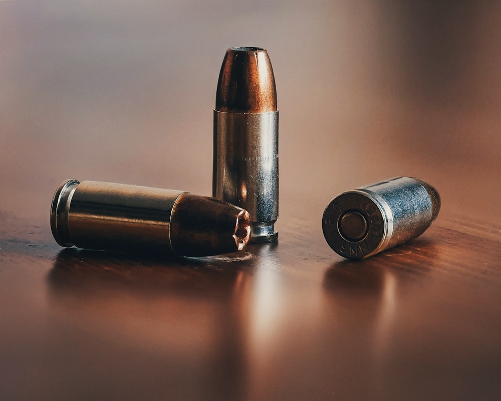 three gray bullets on brown surface