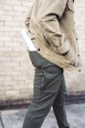 man walking hand on jacket's pocket with rolled paper on pants back pocket