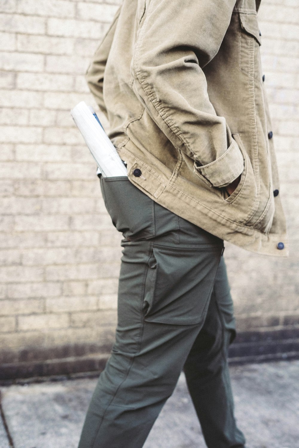 uomo che cammina con la mano sulla tasca della giacca con carta arrotolata sulla tasca posteriore dei pantaloni