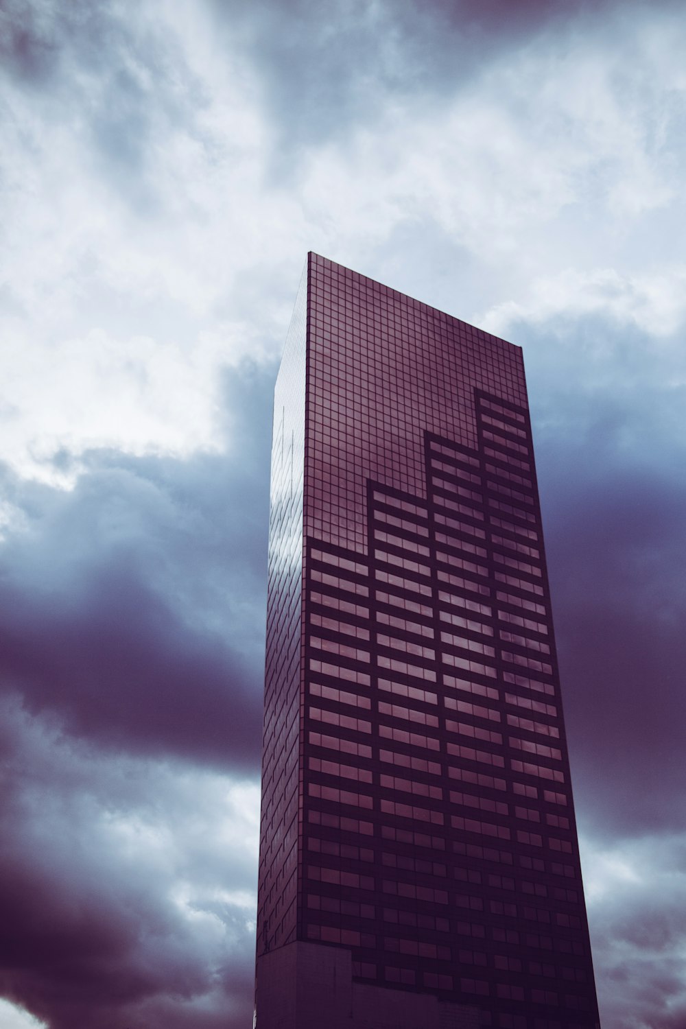 low-angle photography of high-rise building under nimbus clouds