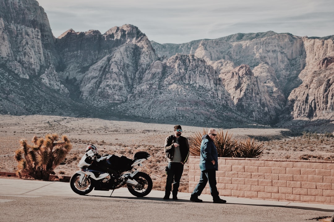 2 men stands on roadside beside parked motorcycle