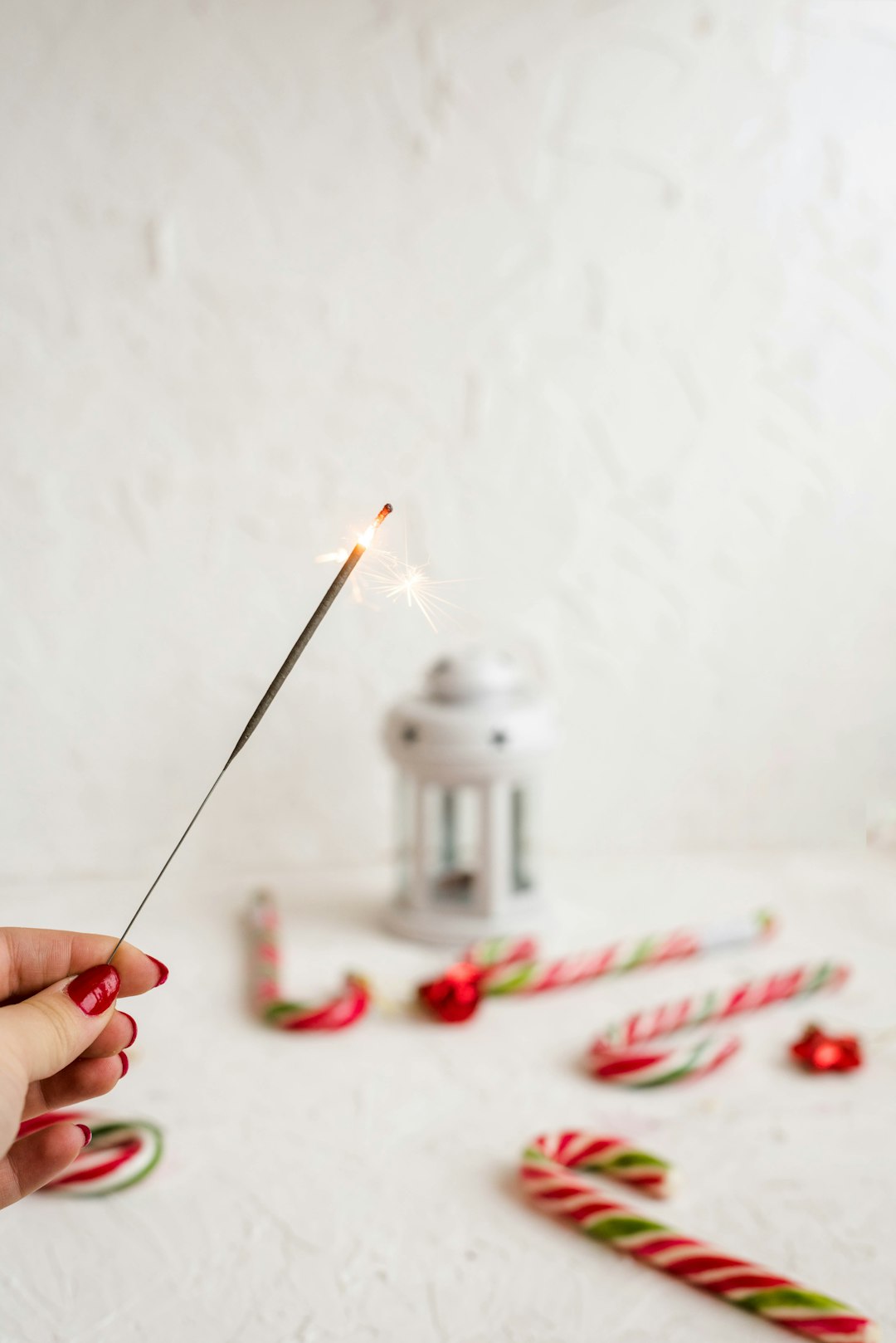 person holding lighted stick beside candy canes